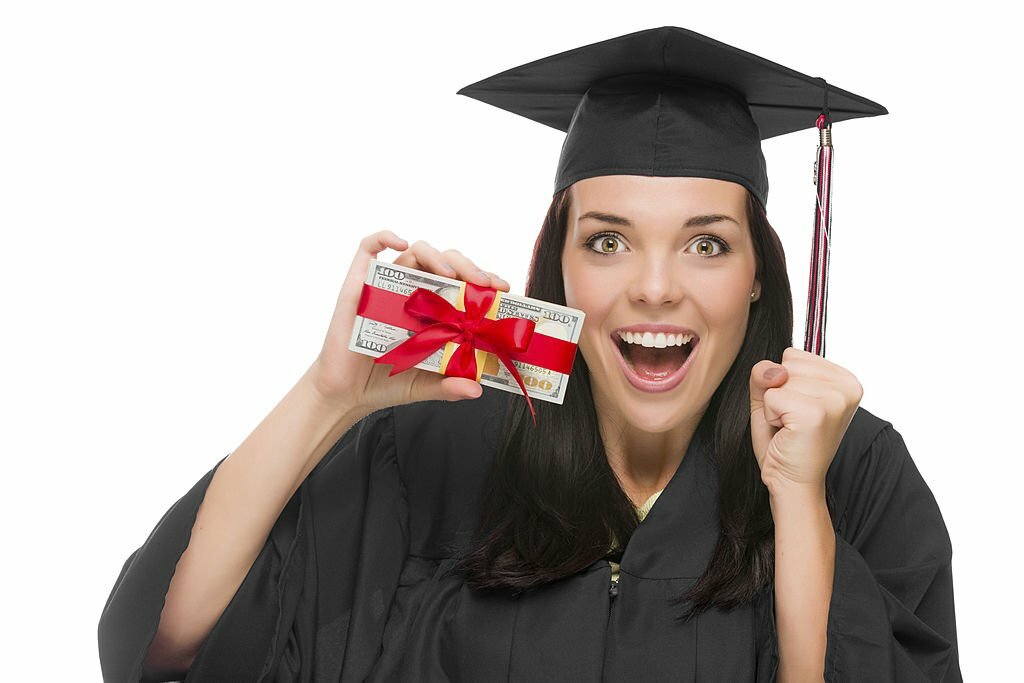 Female Graduate in Cap and Gown Holding Stack of Gift Wrapped Hundred Dollar Bills on a White Background.